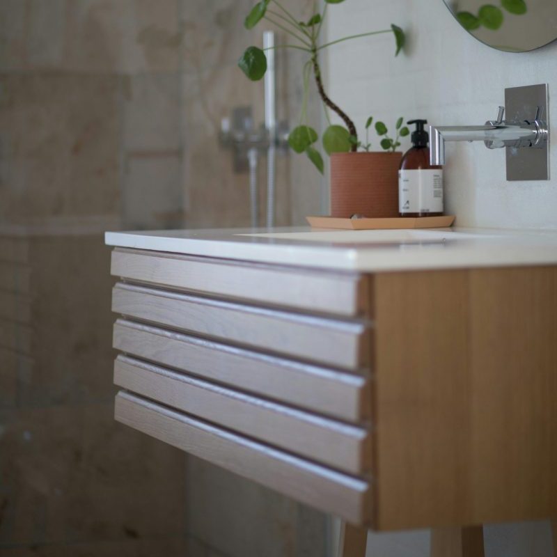 Contemporary bathroom featuring a sleek sink, wooden vanity, and green potted plant decor.